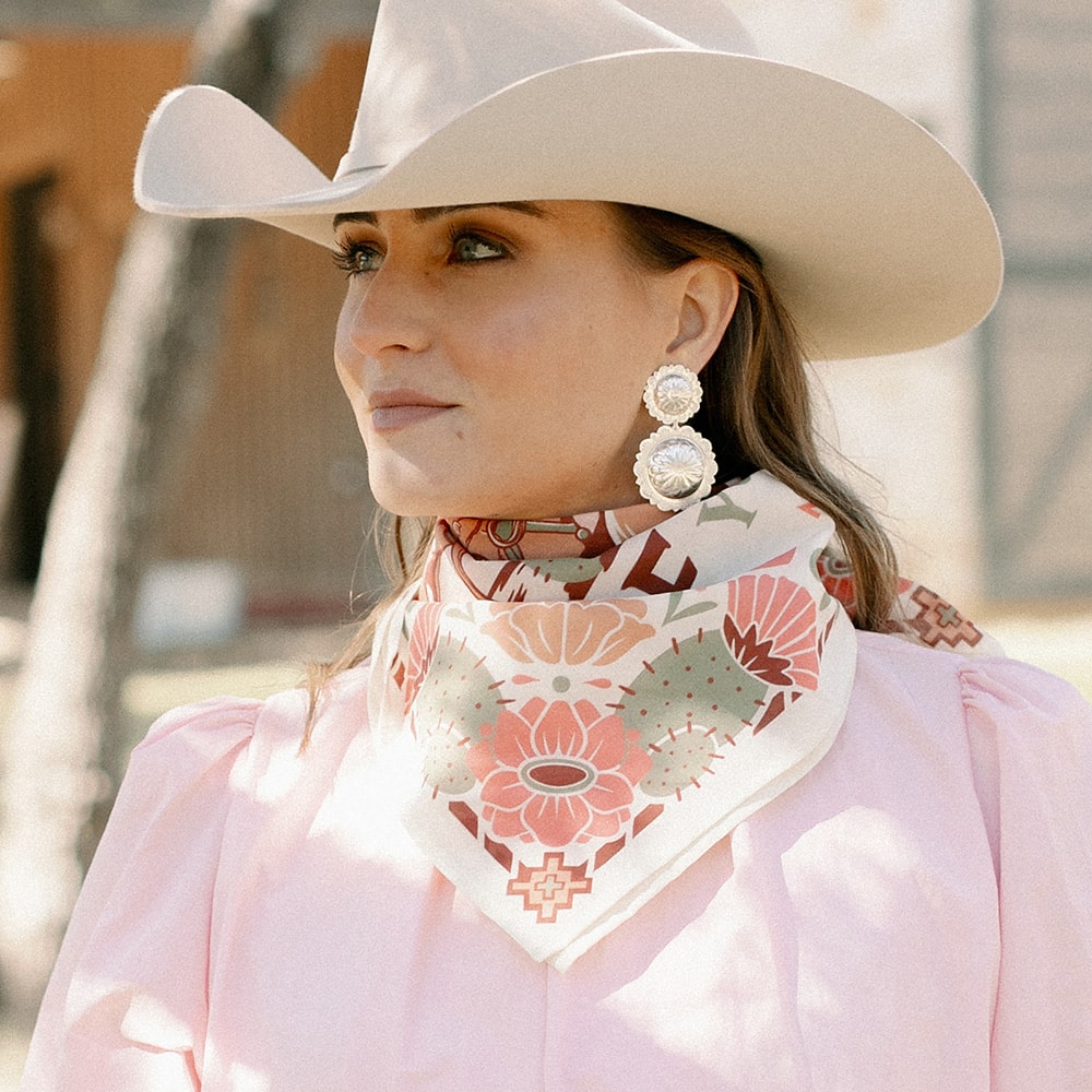 A woman wearing Concho Queen Dangle Earrings by Shop Marian and a pink shirt.