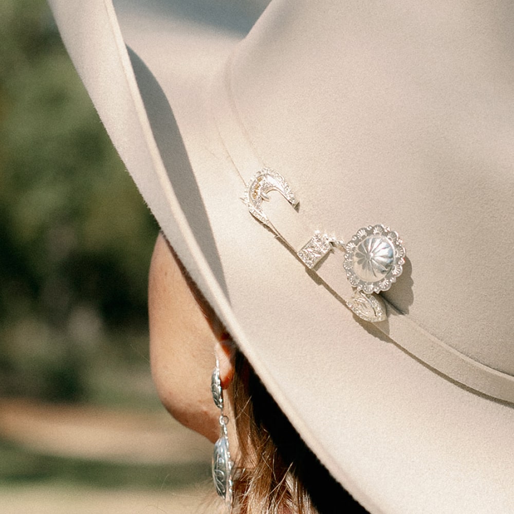 a woman wearing a Concho Queen Hat Pin by Shop Marian and earrings.