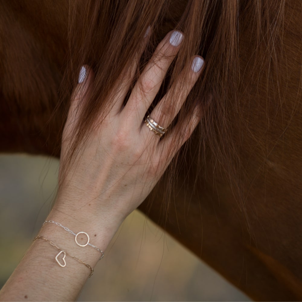 A woman's hand is touching the Shop Marian Take Heart Bracelet.