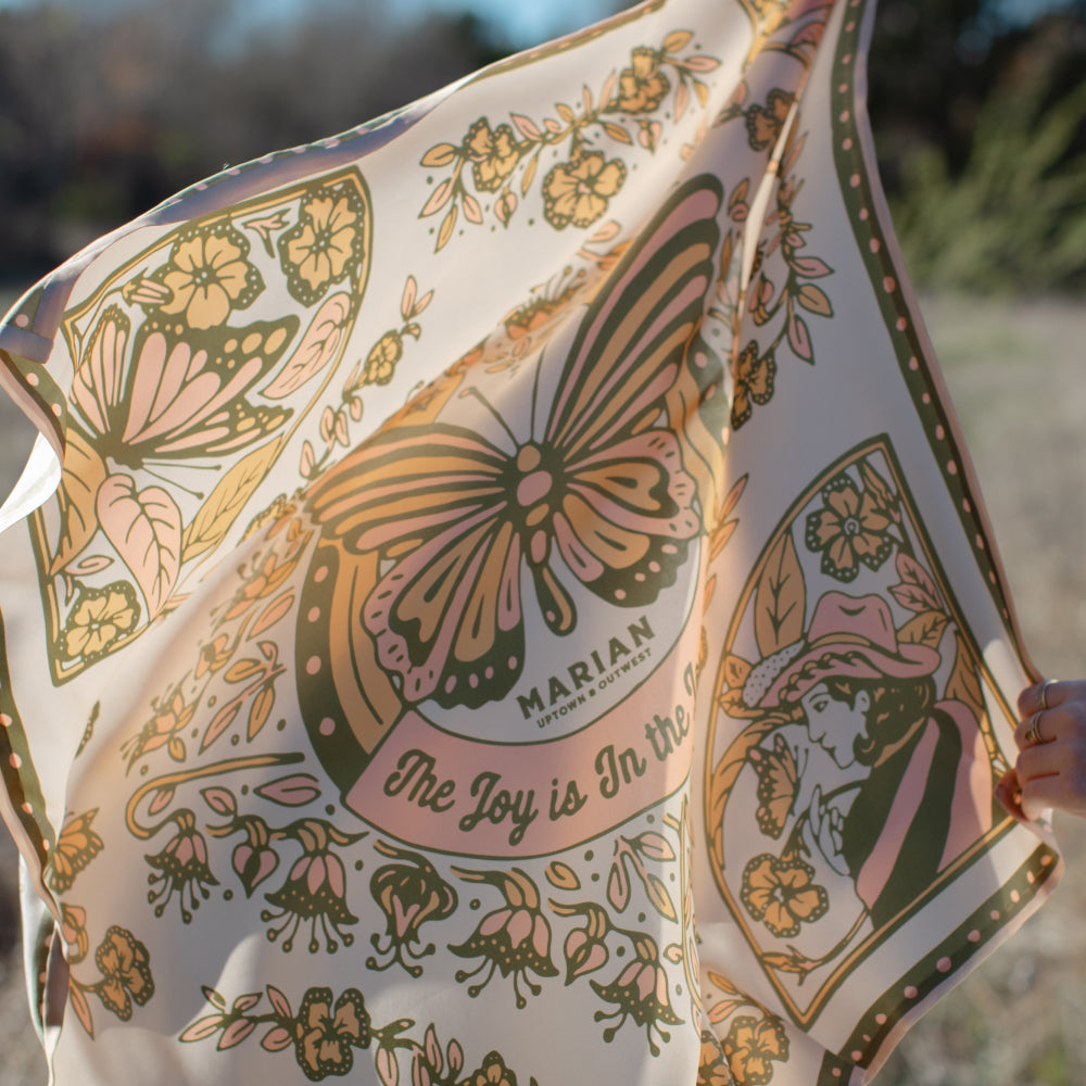 A woman showcases her strength as she holds a Butterfly Scarf adorned with a beautiful butterfly design by Shop Marian.