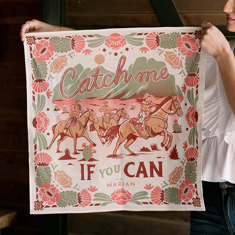 A woman holding up a Catch Me Scarf by Shop Marian that says catch me if you can.