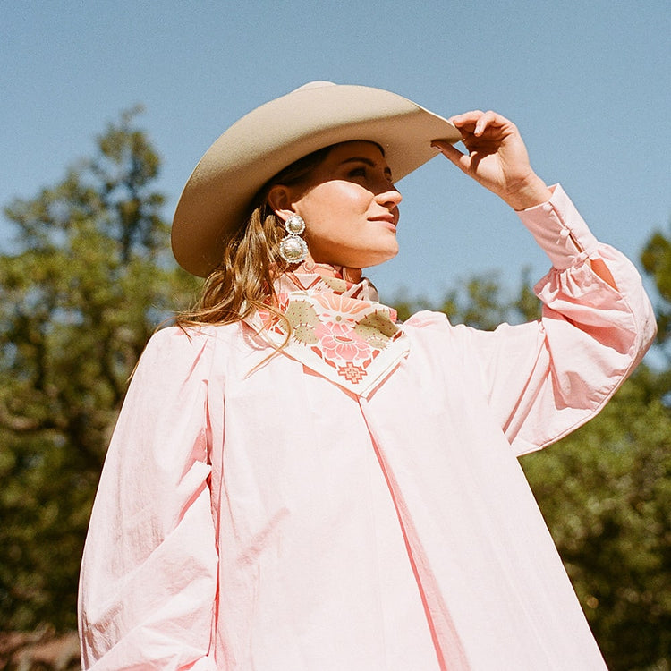 A woman wearing a pink Catch Me Scarf by Shop Marian and cowboy hat.