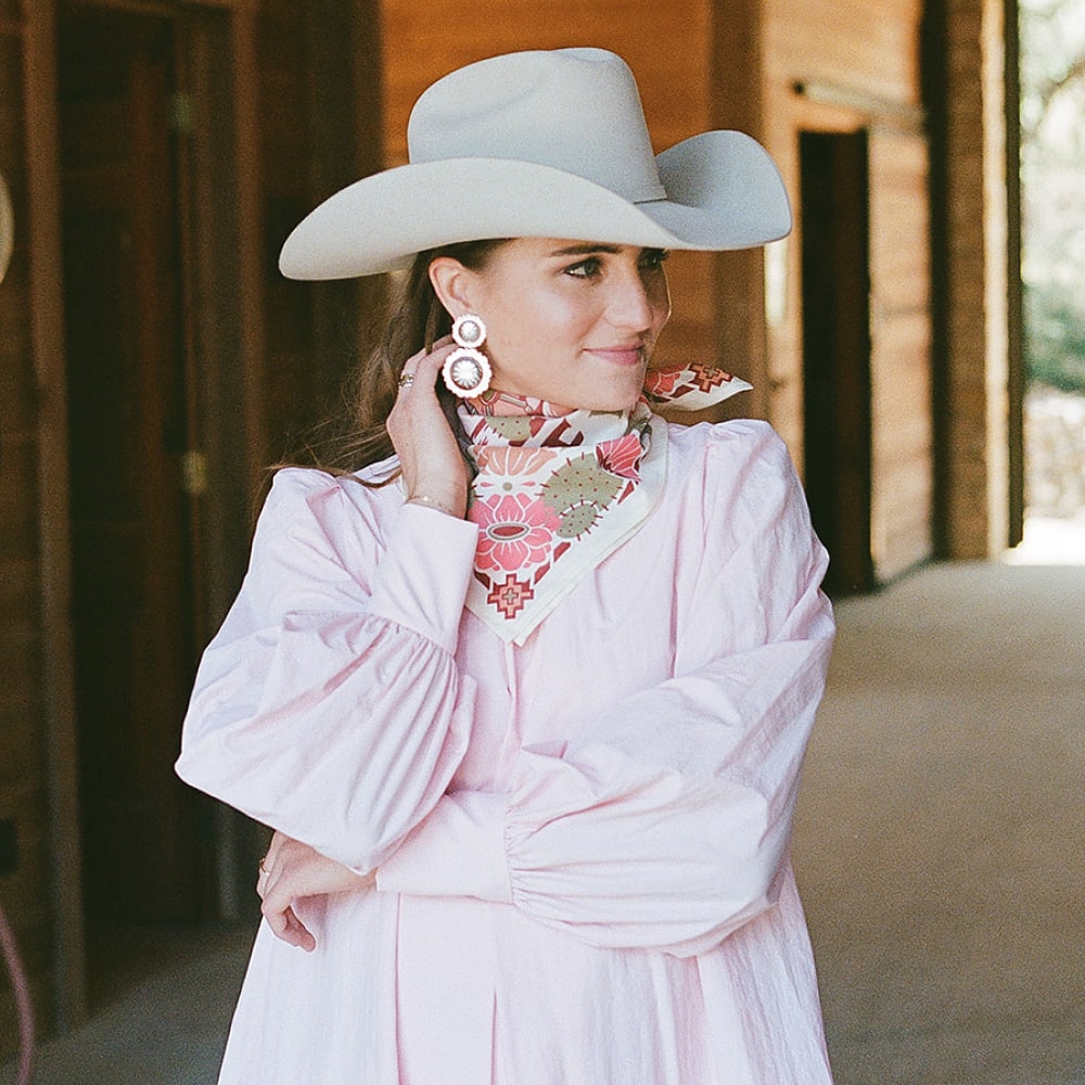 A woman wearing a Catch Me Scarf by Shop Marian and a cowboy hat and pink dress.