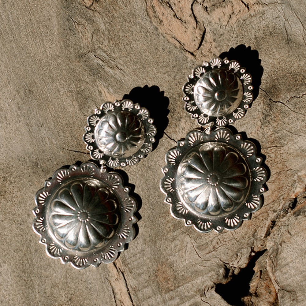 A group of Concho Queen Dangle Earrings by Shop Marian on a wood surface.