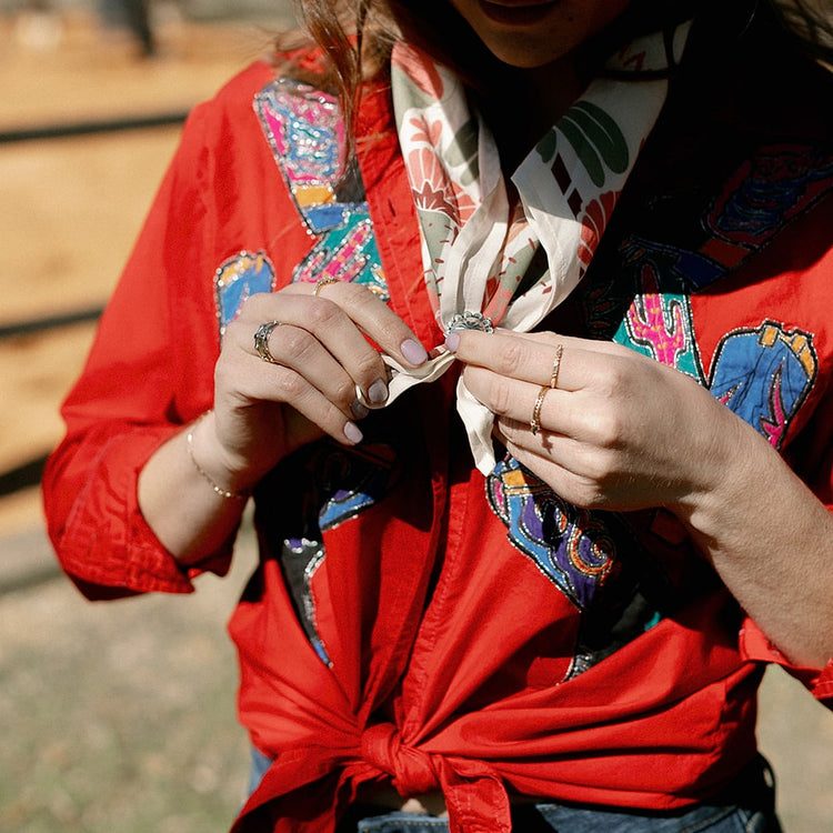 a woman wearing a red shirt and a Concho Queen Scarf Slide by Shop Marian.