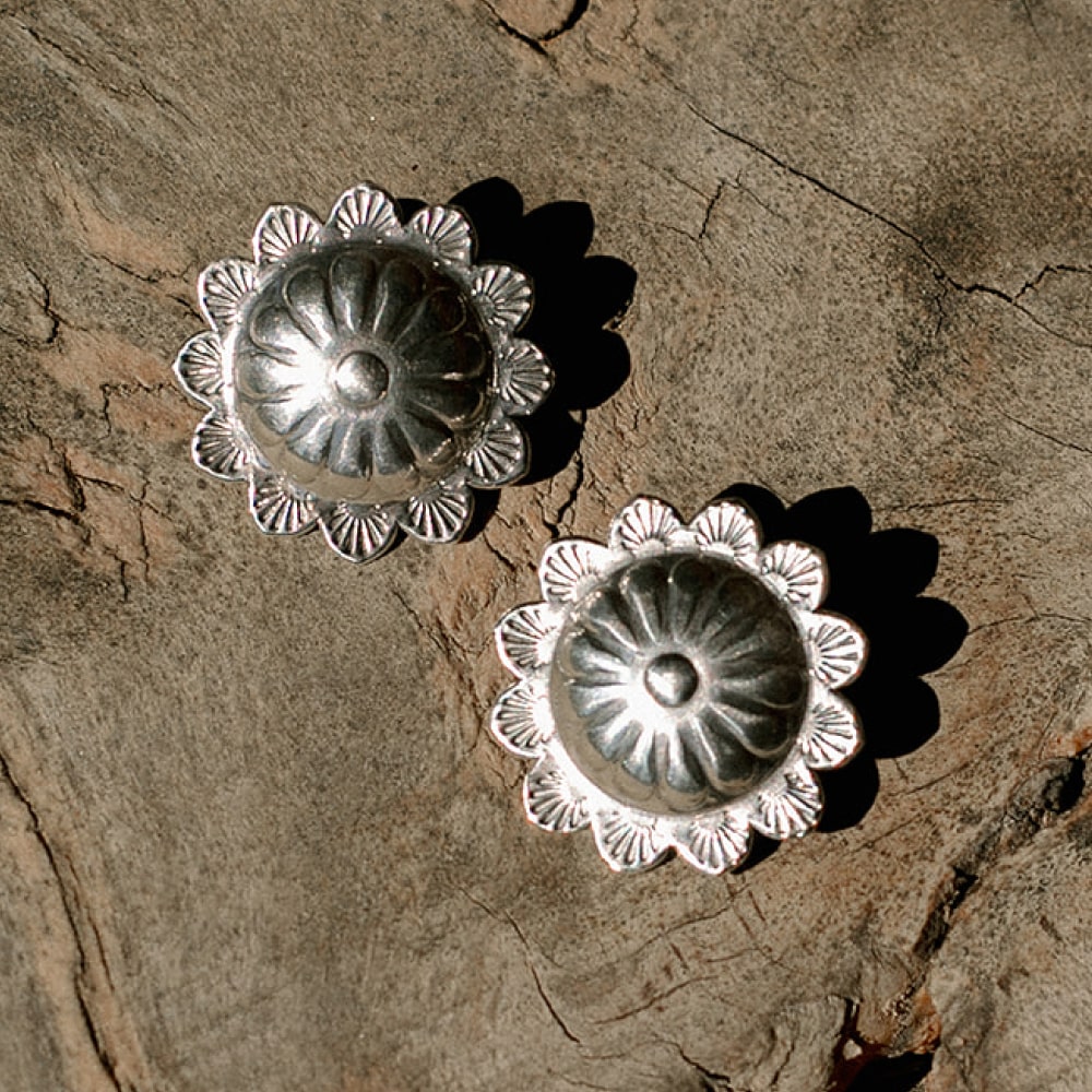 A pair of Concho Queen Studs by Shop Marian on a wood surface.