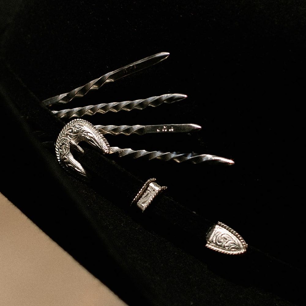A black Cowboy Toothpicks hat with a silver Shop Marian hat pin.