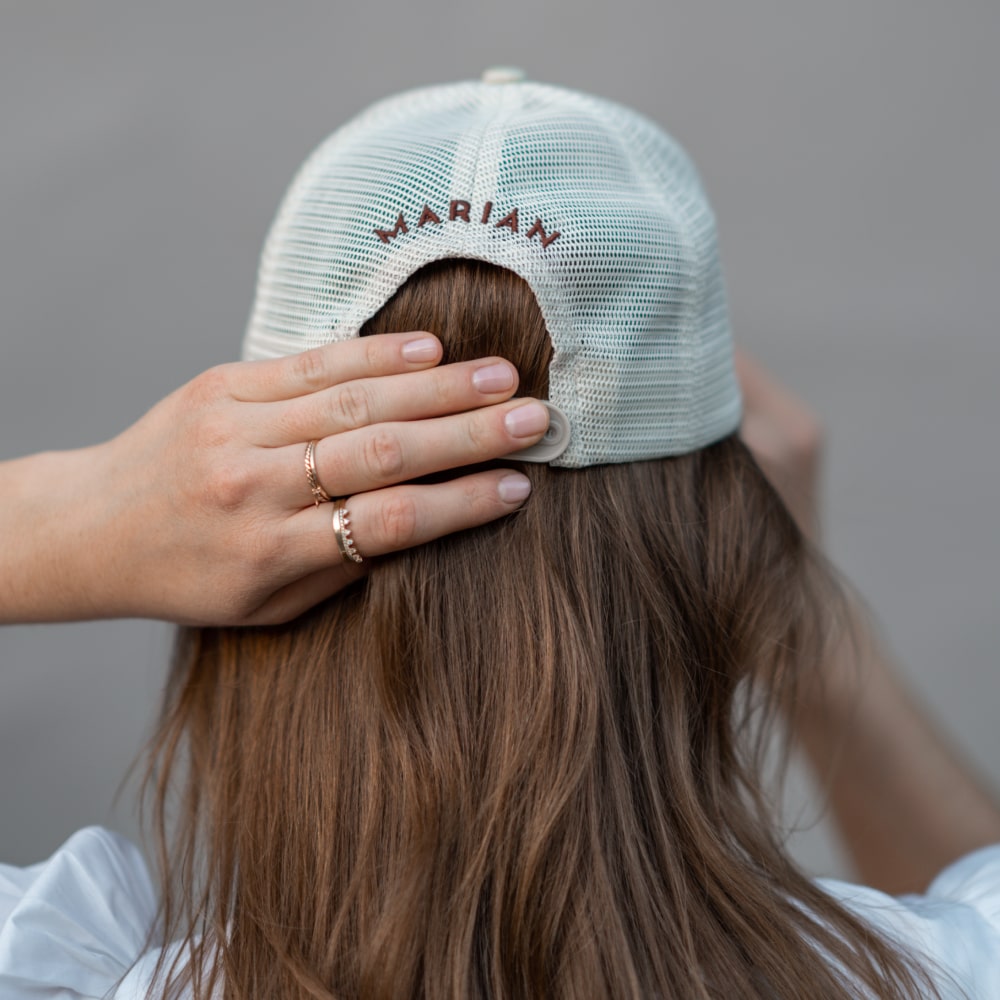 A woman wearing a Darling Cap with the brand Shop Marian on it.