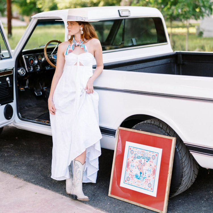 a woman in a white dress standing next to a white pickup truck, wearing the Darling Print by Shop Marian.