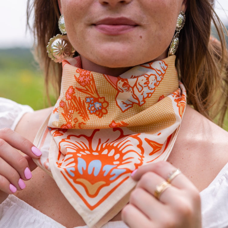 A woman wearing a Grow Good Things Scarf by Shop Marian with a floral pattern.