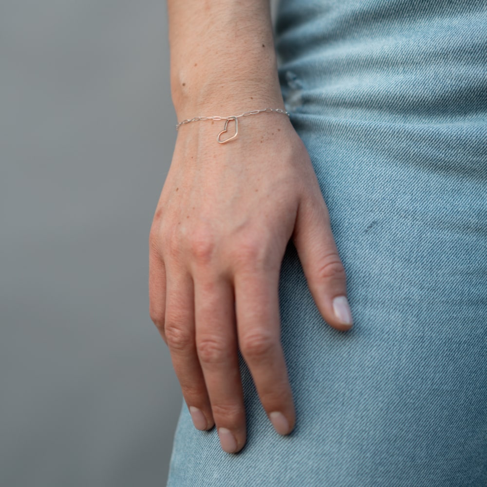 A woman's hand with a Take Heart Bracelet by Shop Marian on it.