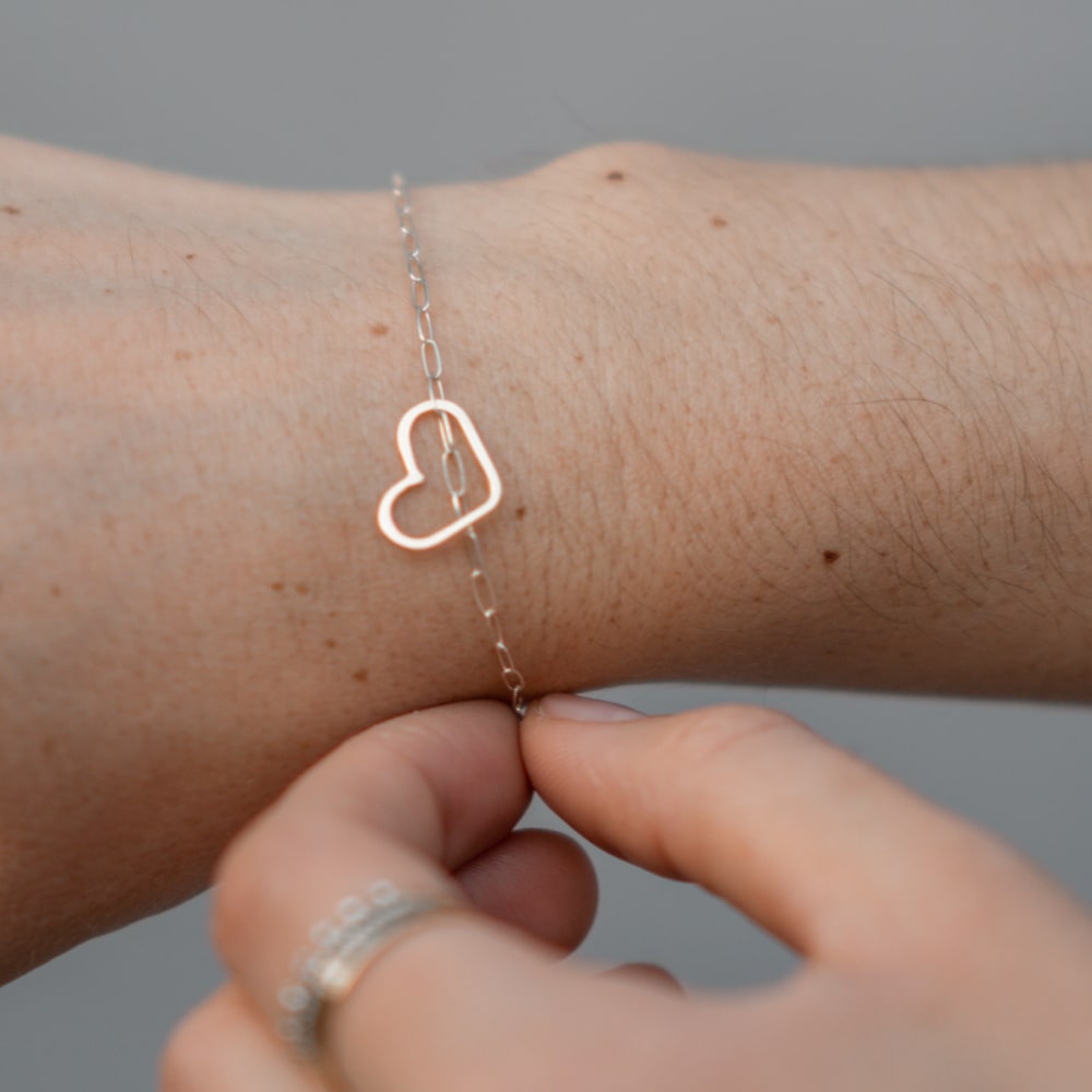 A woman wearing a Take Heart Bracelet with a heart on it from Shop Marian.