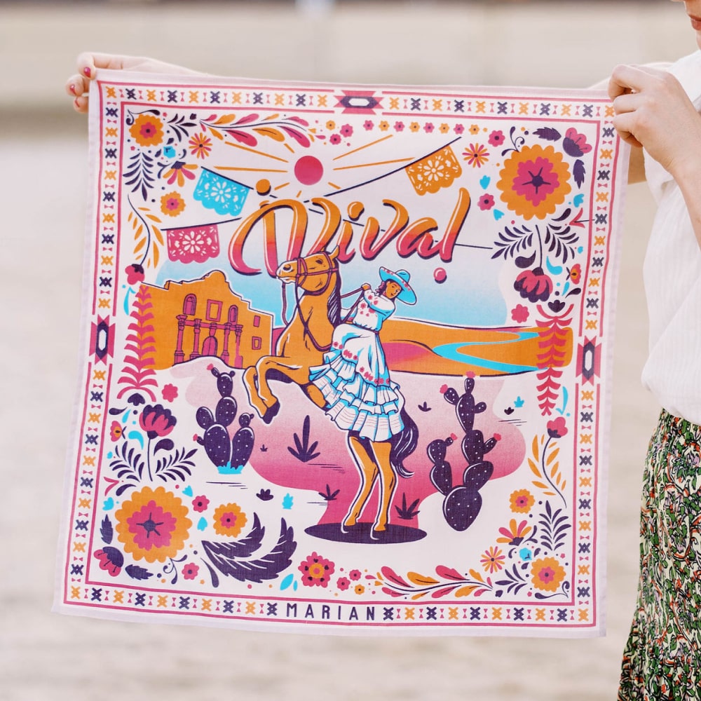 a girl holding up a colorful ¡VIVA! Scarf with a horse on it from Shop Marian.