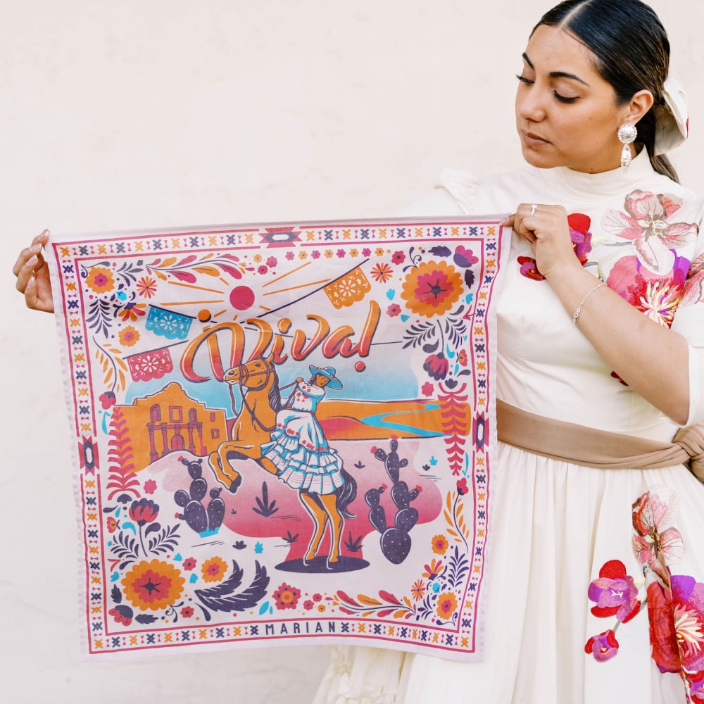 a woman in a floral dress holding a ¡VIVA! Scarf by Shop Marian.